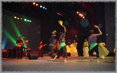 Bailarines y músicos comparten un escenario con iluminación de colores