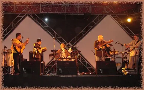 Presentación con guitarras y percusión bajo una estructura de luces